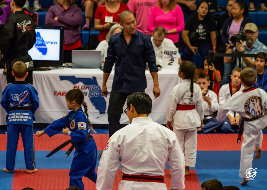 man watches as children compete in tae kwon do forms tournament
