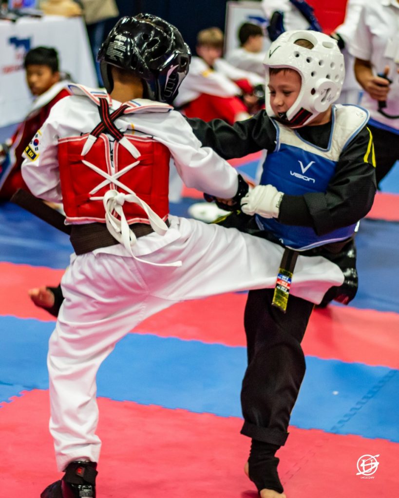 two uniformed boys sparring in tae kwon do tournament