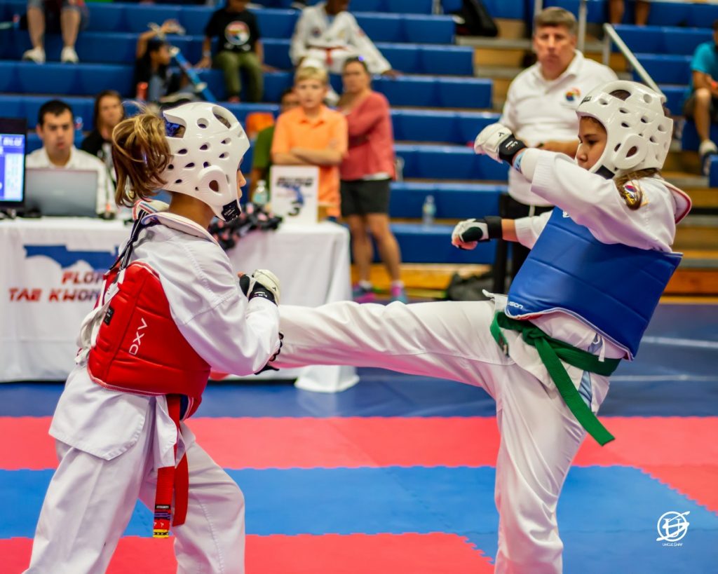 two uniformed girls sparring in tae kwon do tournament