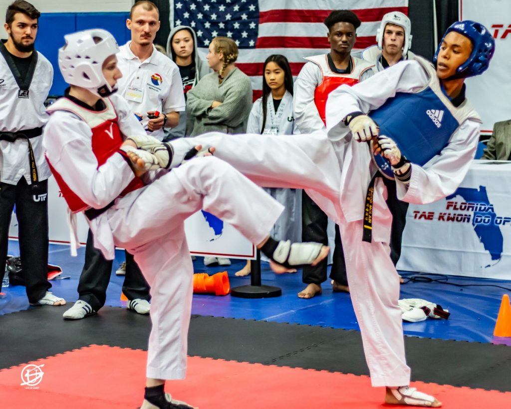 two uniformed young men sparring in tae kwon do tournament